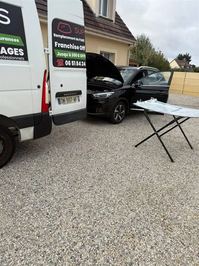 Camion Super Glass en intervention dans l'allée d'un client, avec un pare-brise neuf prêt à être posé